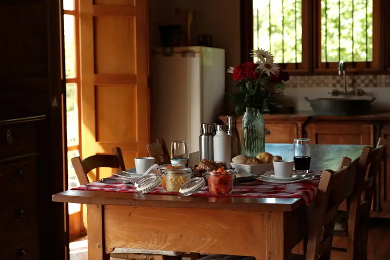 A dining table laid for a shared meal in a warm, sunlit room.